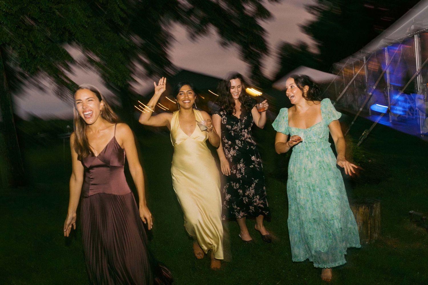 A group of women celebrate together at an outdoor evening wedding reception.