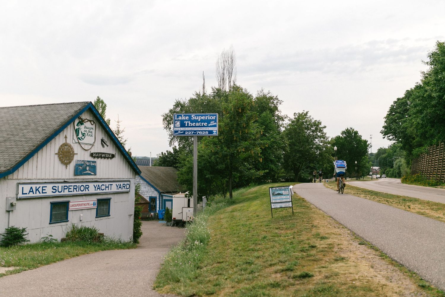 A small building with a sign for Lake Superior Lodge sits next to a rural road with directional signage.