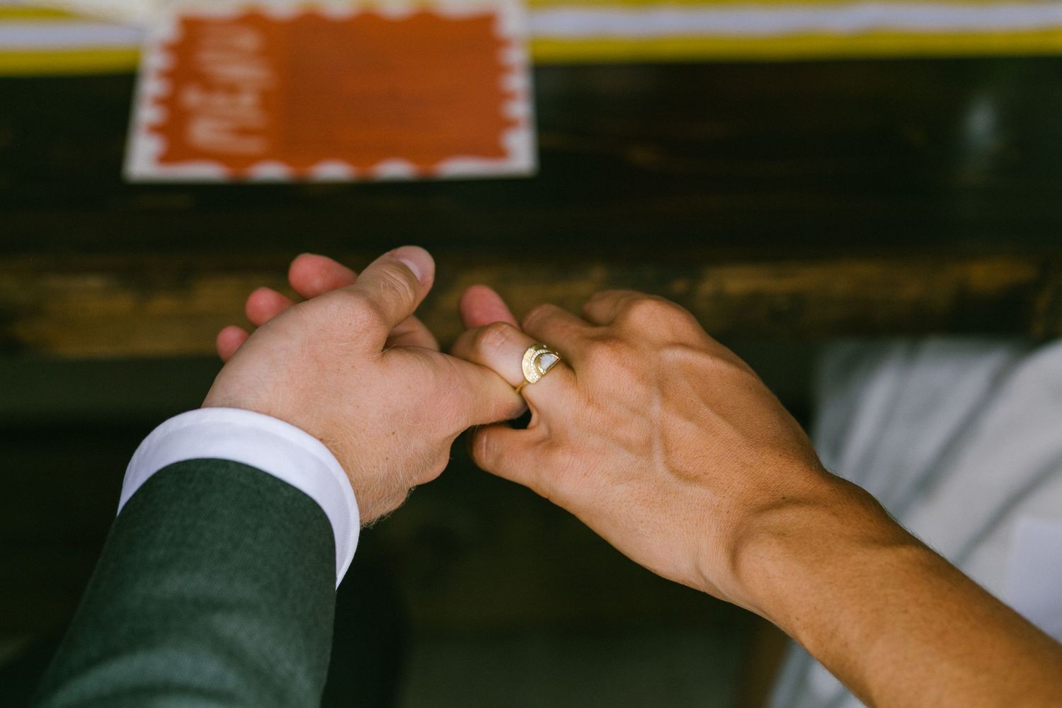 Two hands hold each other tenderly against a dark background in a romantic gesture.