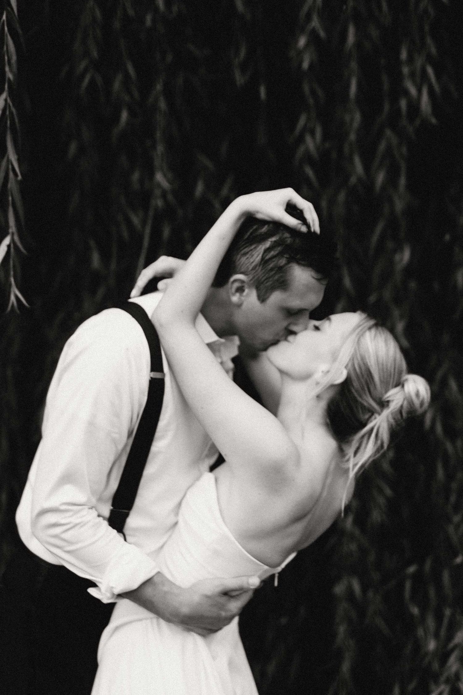 A romantic black and white photo series shows a couple in wedding attire sharing passionate kisses against a dark background.