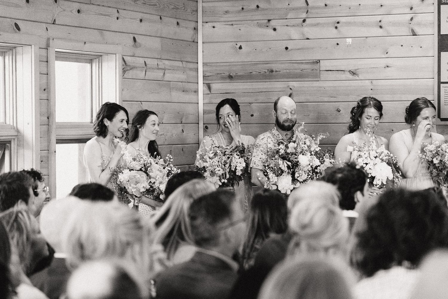Wedding reception guests seated in rows at a rustic wooden venue.