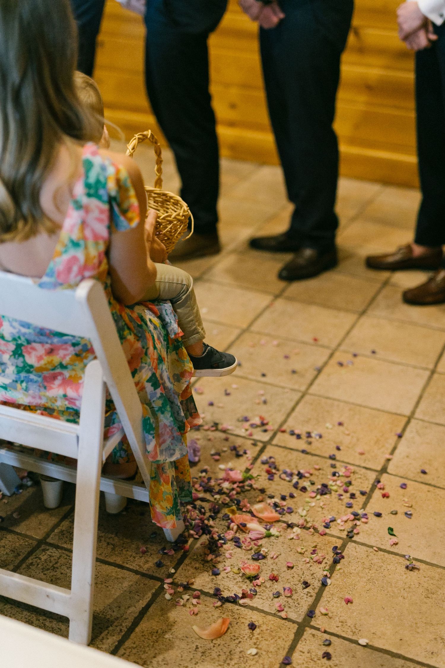 Scattered confetti on a tiled floor near a floral dress at a wedding reception.