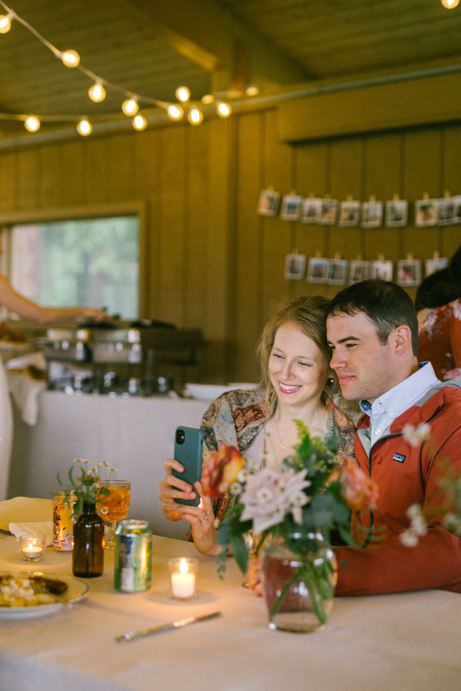 A cozy reception scene with string lights and mason jar centerpieces on wooden tables.