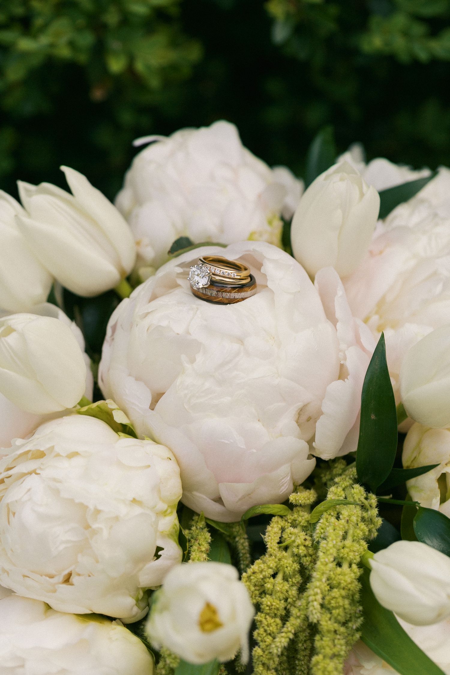 Wedding rings displayed on delicate white peonies with yellow floral accents.