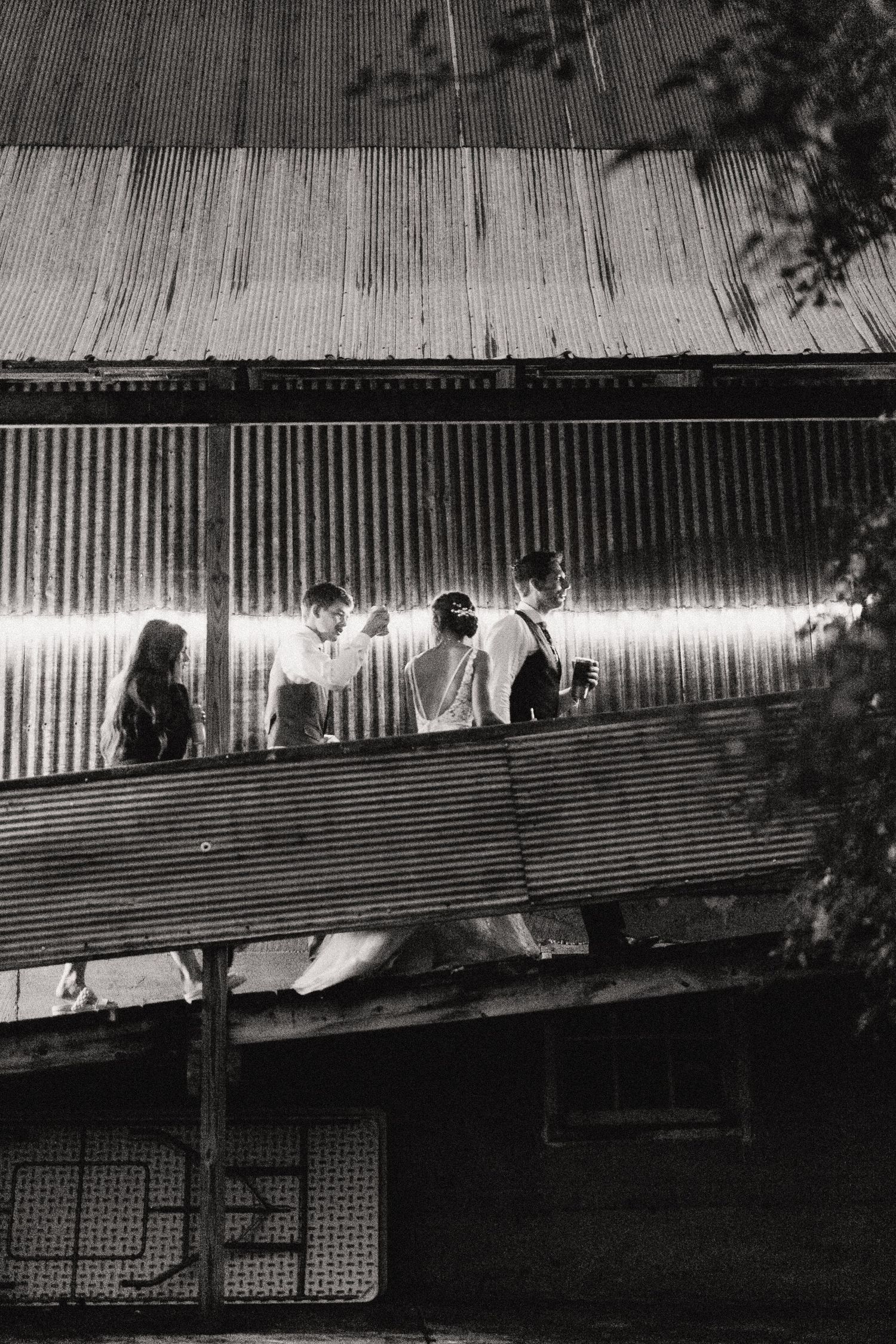 Black and white photo of silhouettes against a corrugated metal wall with dramatic lighting.