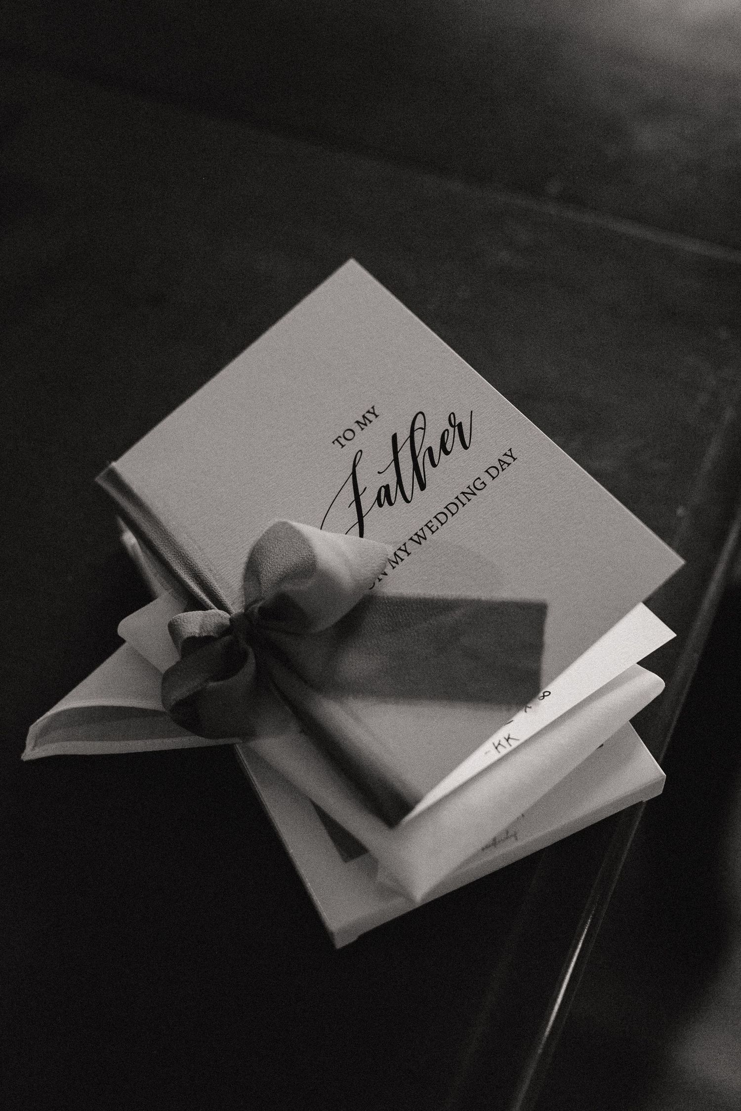 Wedding invitations with elegant black ribbon bows arranged in monochrome setting.