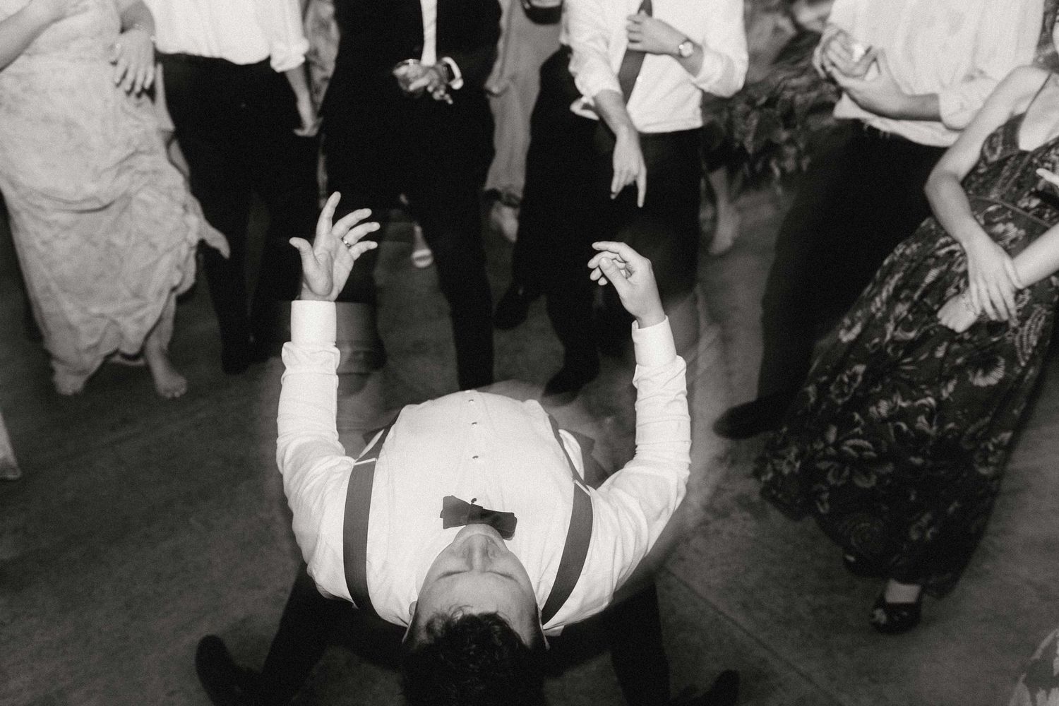 A couple dancing together at a social gathering with other dancers visible in the background.