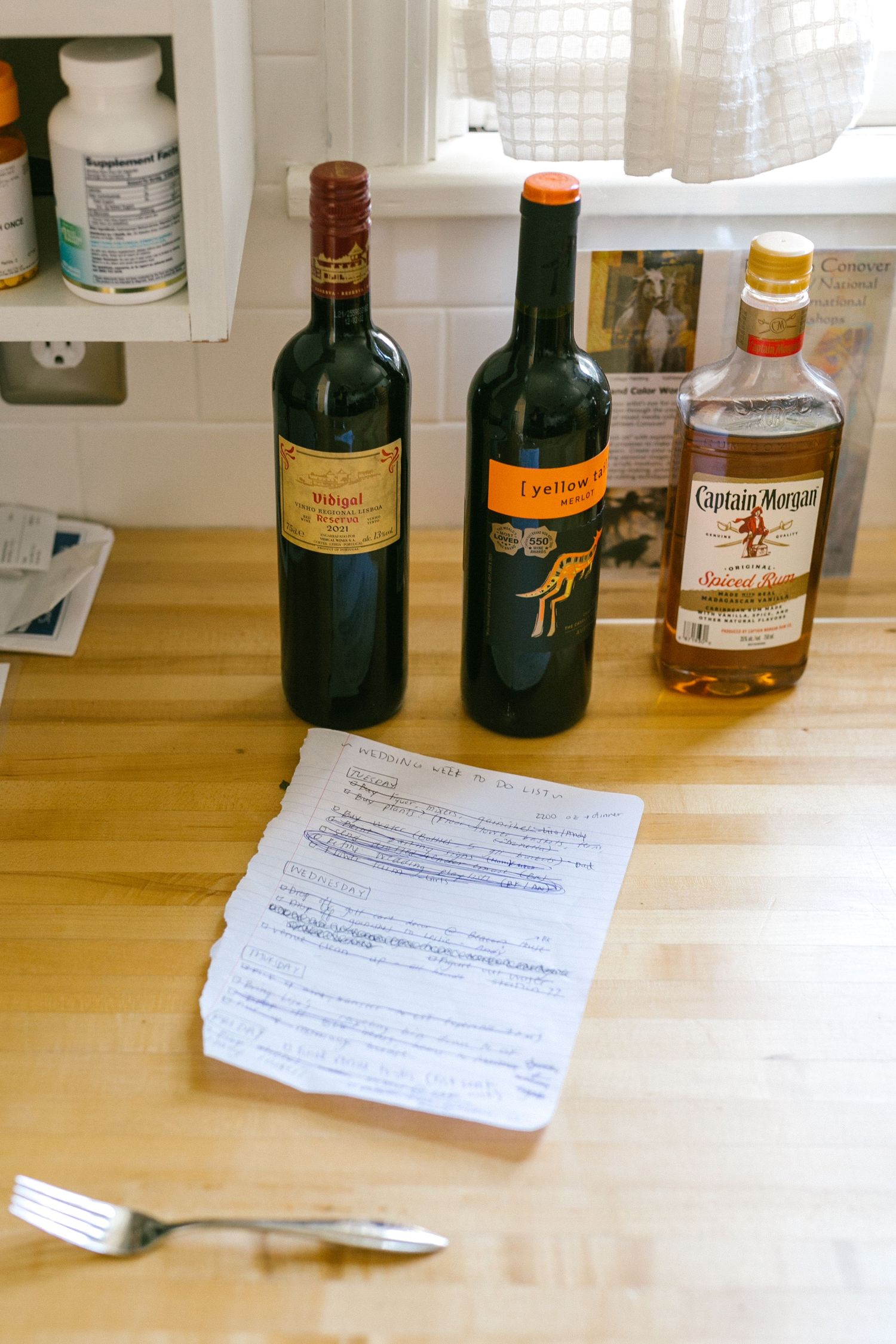 Various liquor bottles and papers arranged on a wooden table surface for a tasting session.
