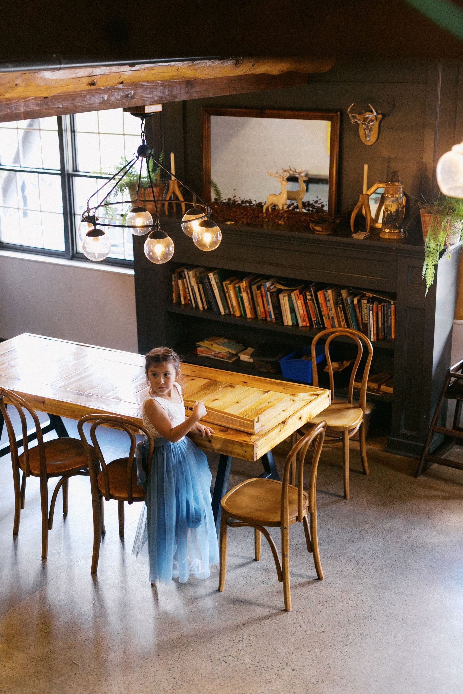 A rustic cafe interior with wooden tables, chairs and bookshelves showing a warm, cozy atmosphere.