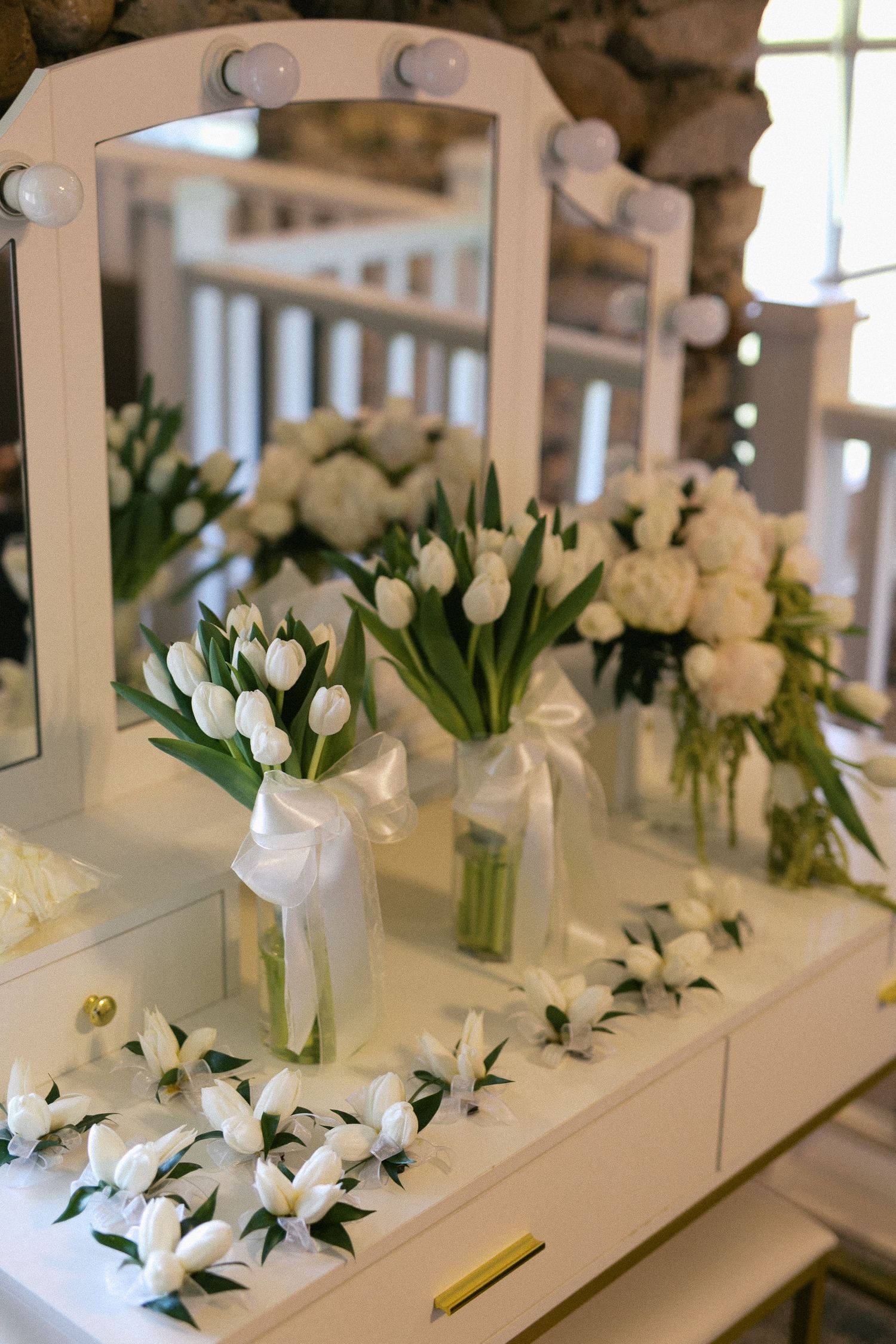 White tulips and floral arrangements displayed on a vanity with mirrors.