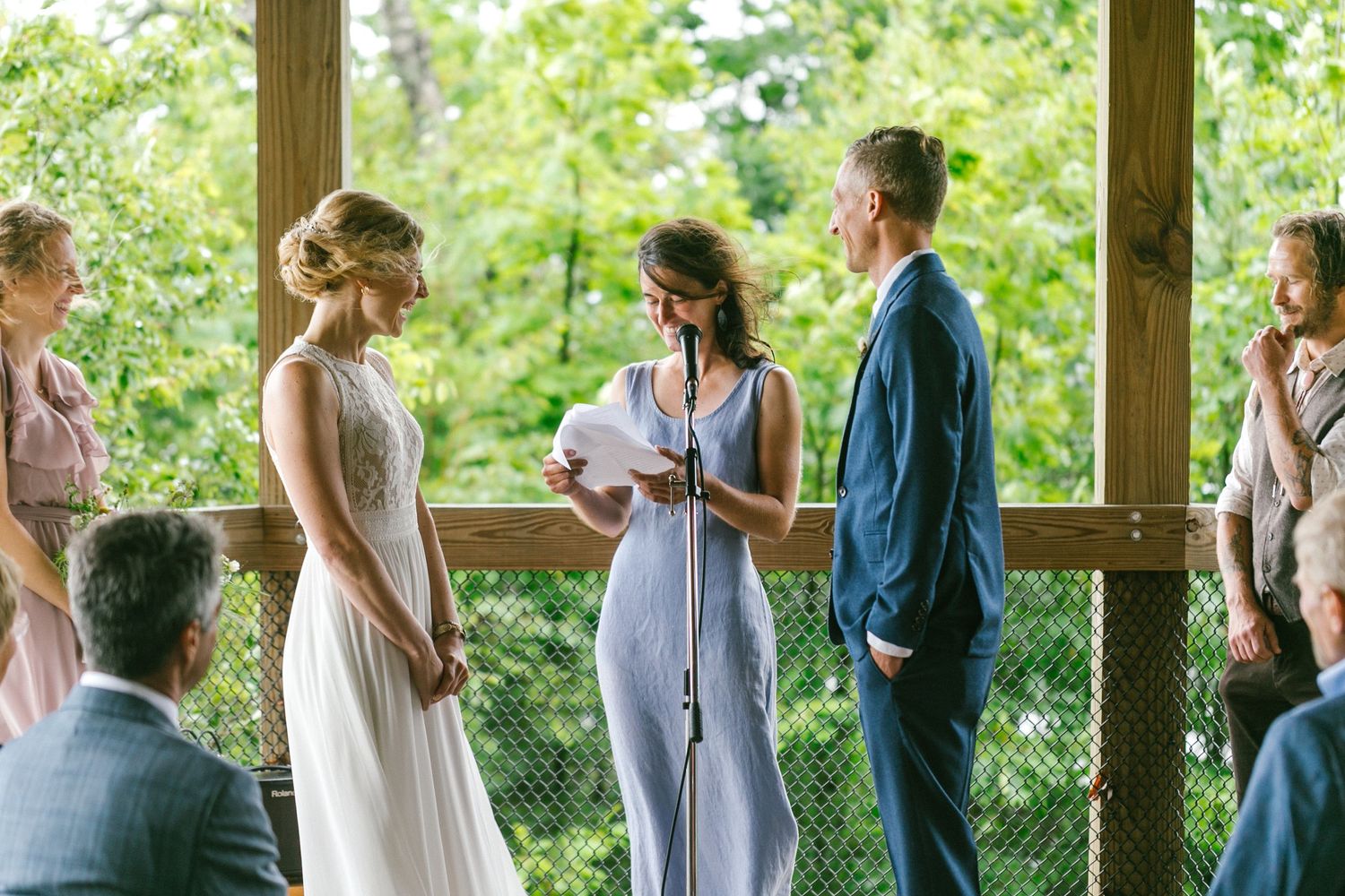 Wedding ceremony in a wooden gazebo with guests gathering to witness the exchange of vows.