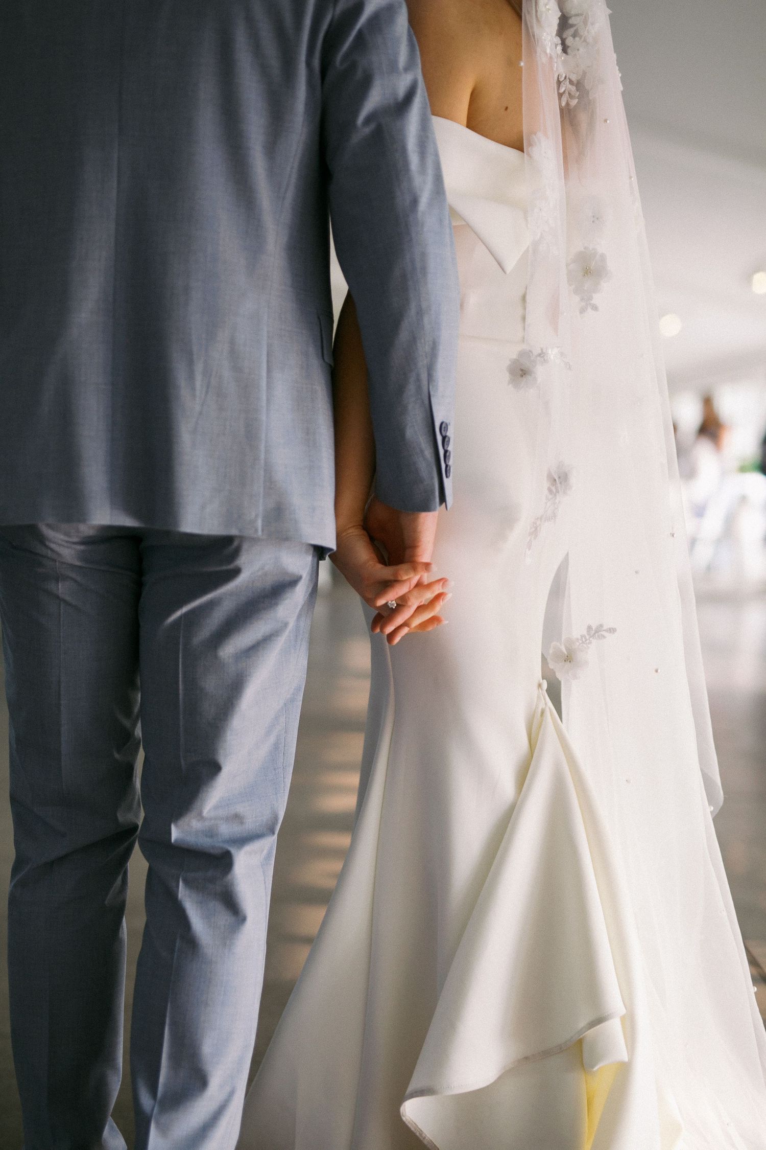 Close-up details of formal attire showing a gray suit next to a white wedding dress.