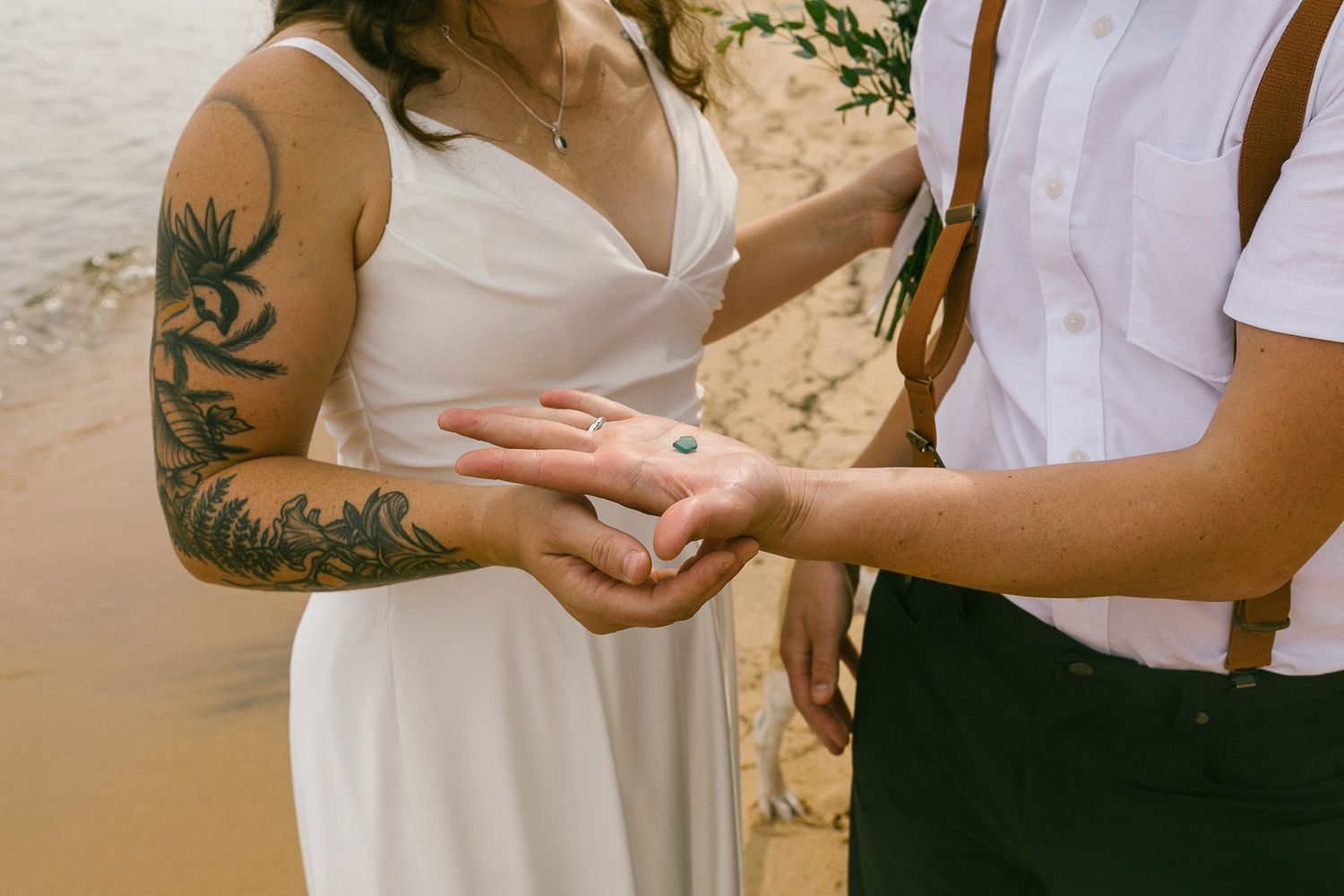 Hands with rings exchange vows during an intimate beach ceremony.