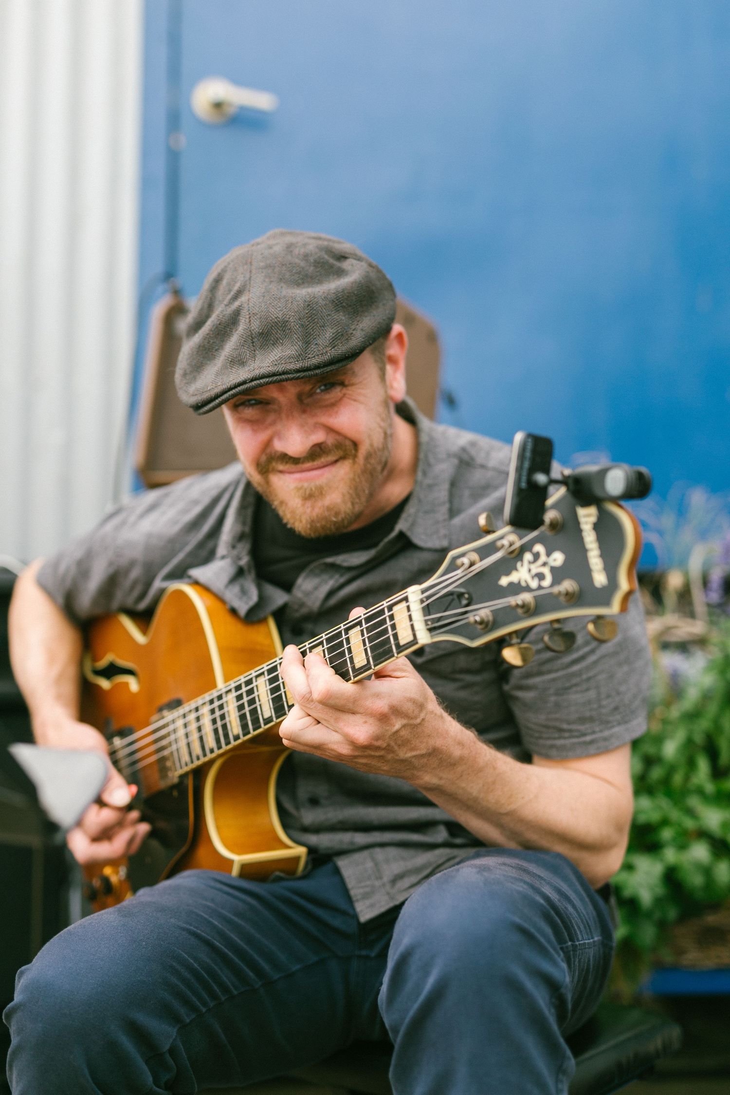 Musician playing an acoustic guitar during an outdoor performance.