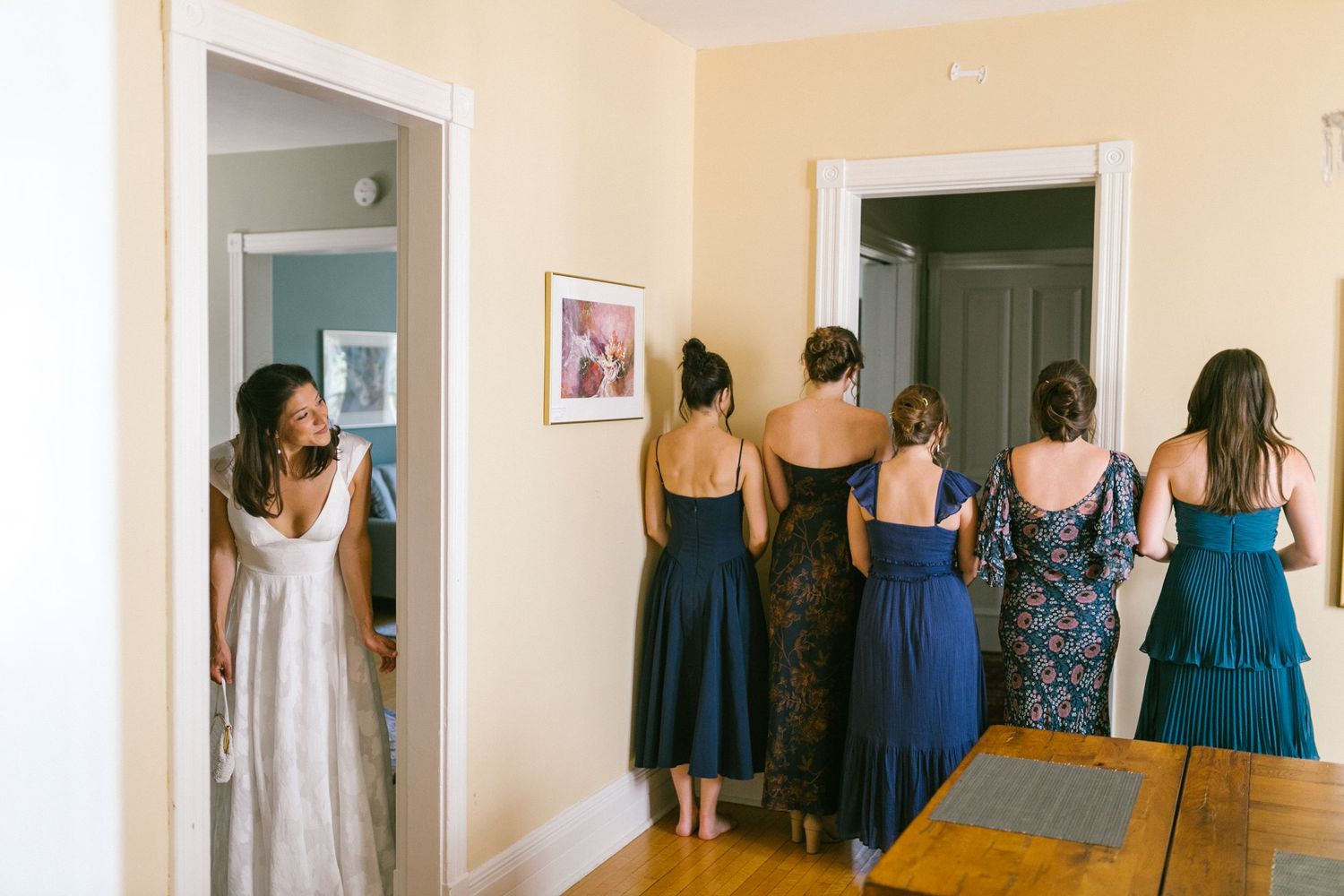 A series of images showing bridesmaids in blue dresses getting ready in a room with cream colored walls.