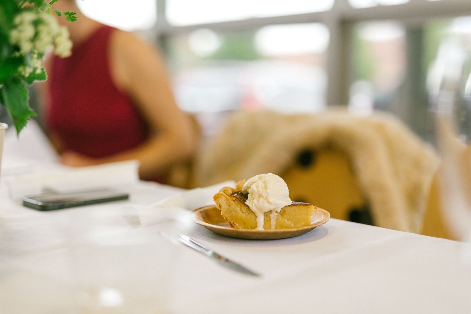 A dessert plate with scoop of ice cream on a white table with a blurred background.