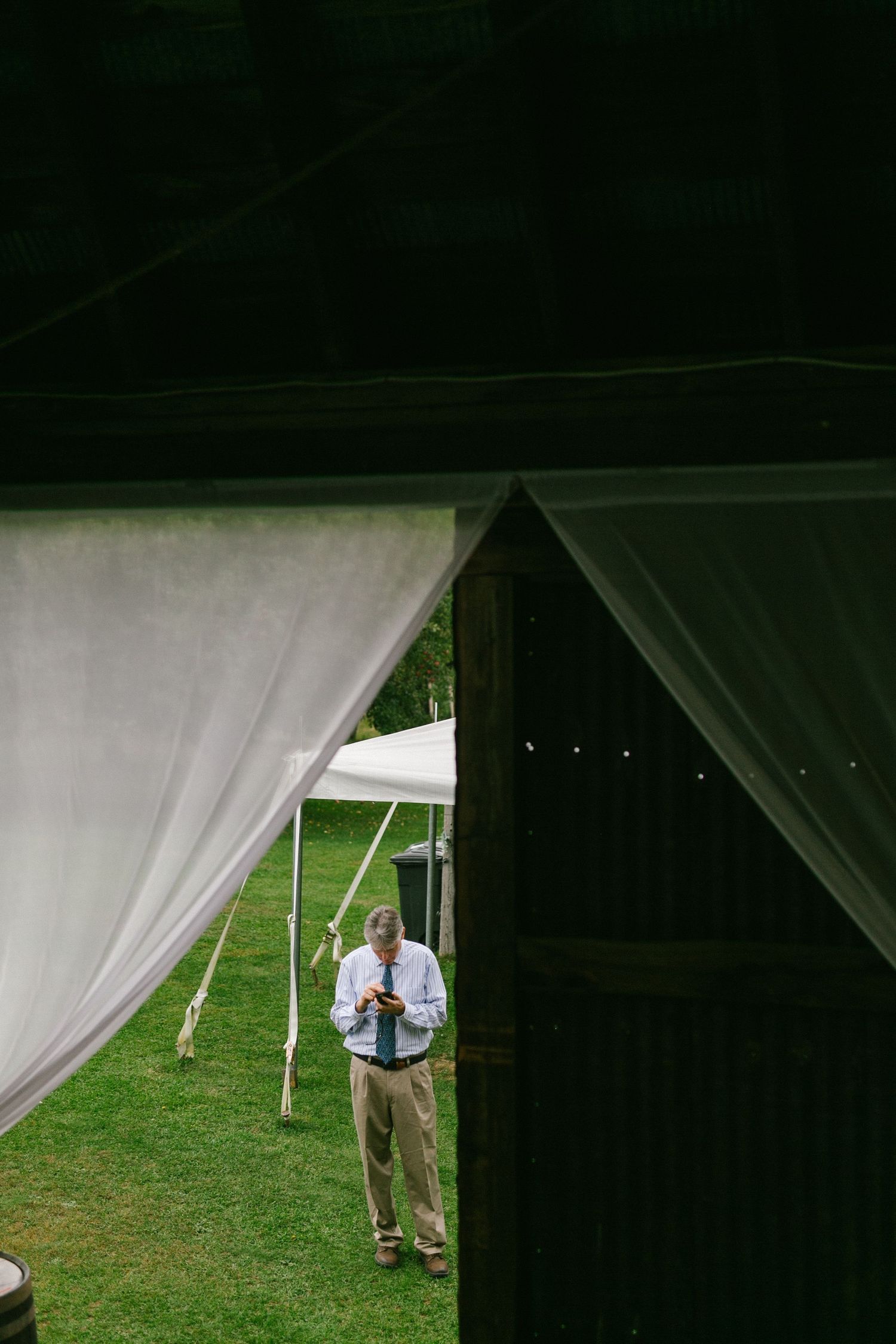 Person standing between white tent curtains at an outdoor event.