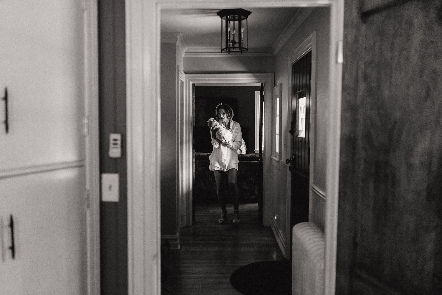 Moody black and white view down a long hallway with dramatic lighting and doorways.