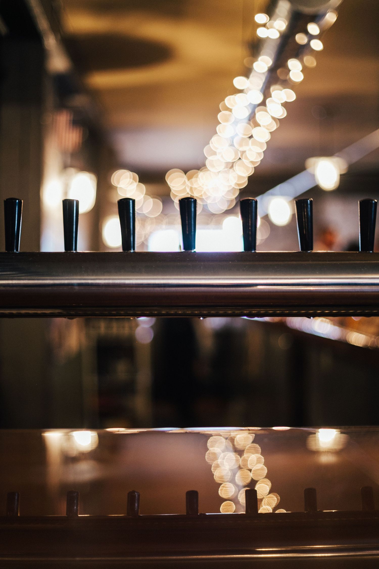 Blurred bokeh lights create an abstract pattern against dark wooden shelves in a dimly lit interior space.