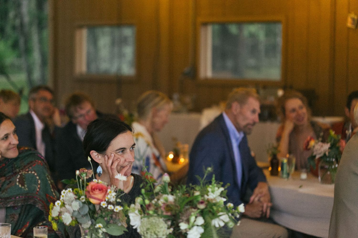 Wedding reception dinner table decorated with floral centerpieces and candlelight.