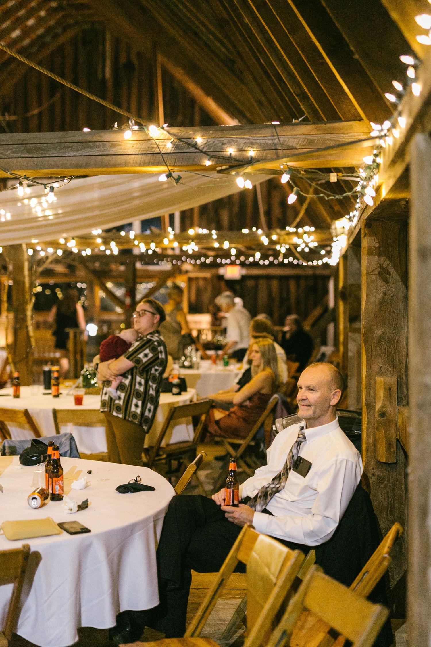 Rustic barn reception venue with string lights and tables decorated for a wedding celebration.