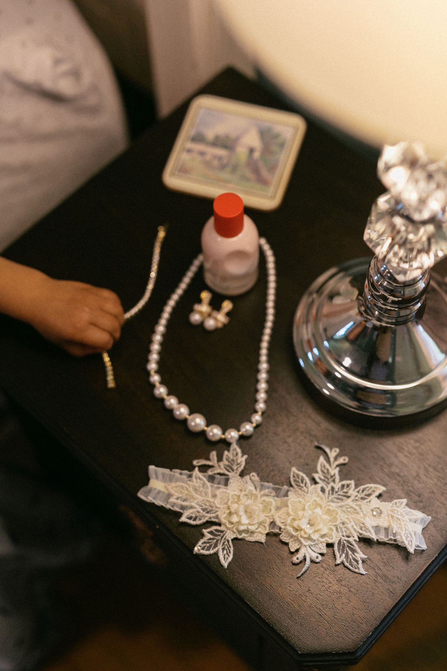 Delicate lace bridal accessories and pearl necklaces displayed on a dark surface.