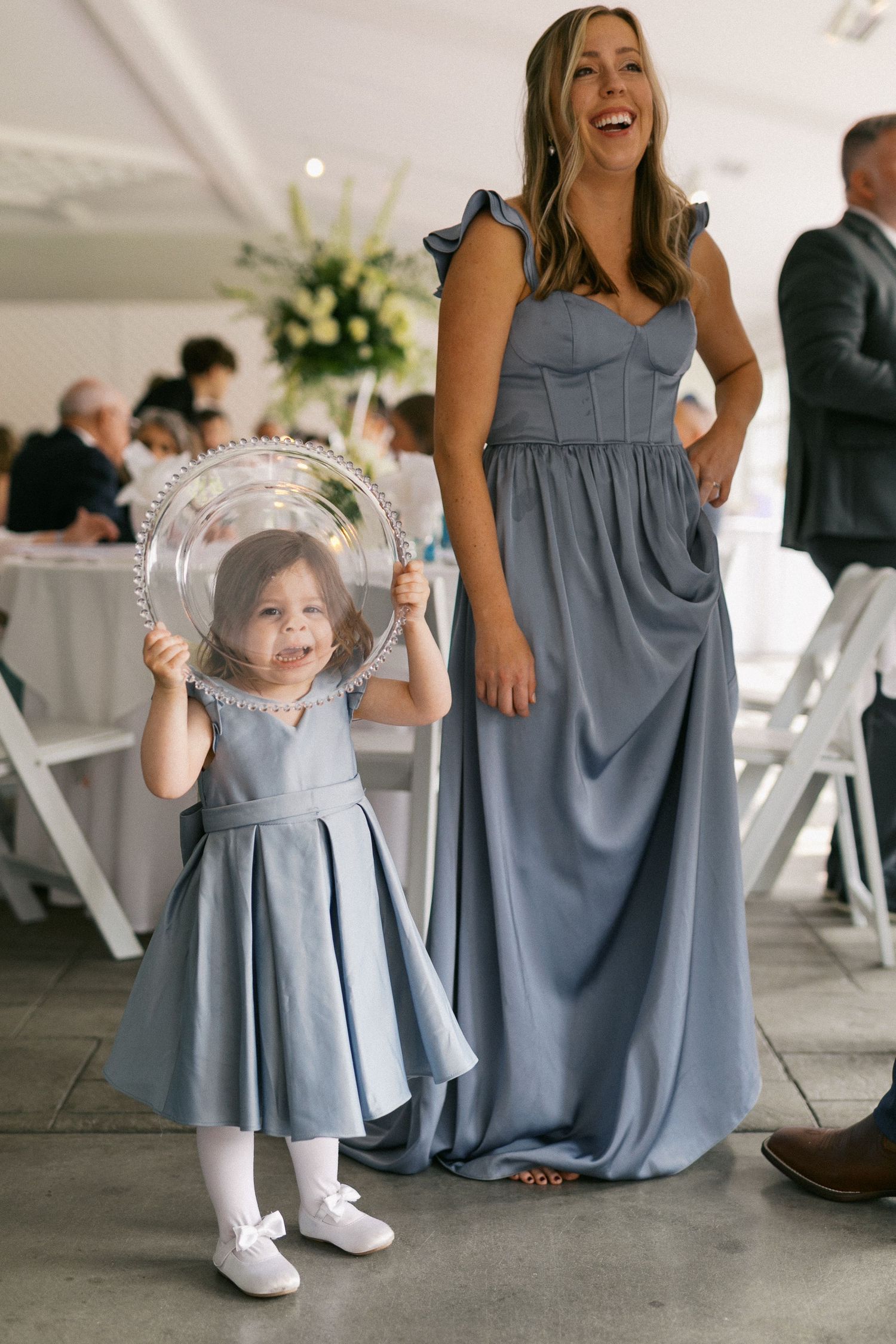 Bridesmaids in light blue dresses stand with young flower girl in matching dress at wedding reception.
