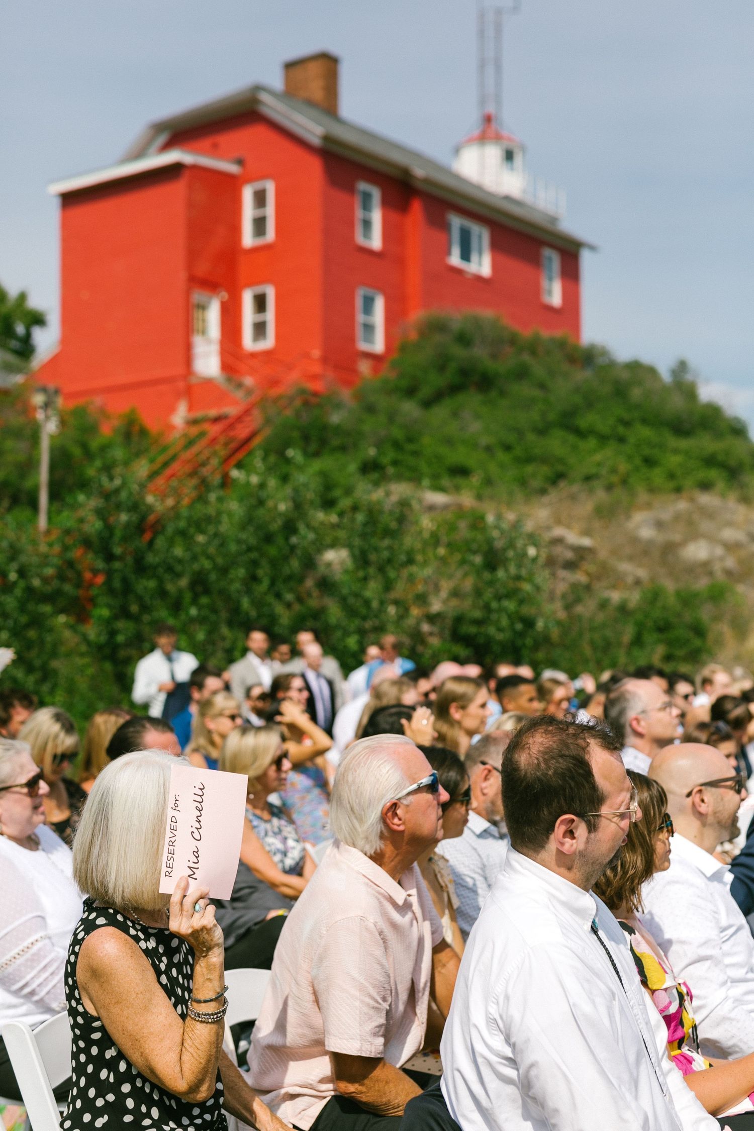 Large crowd gathered outdoors near a distinctive red lighthouse building.