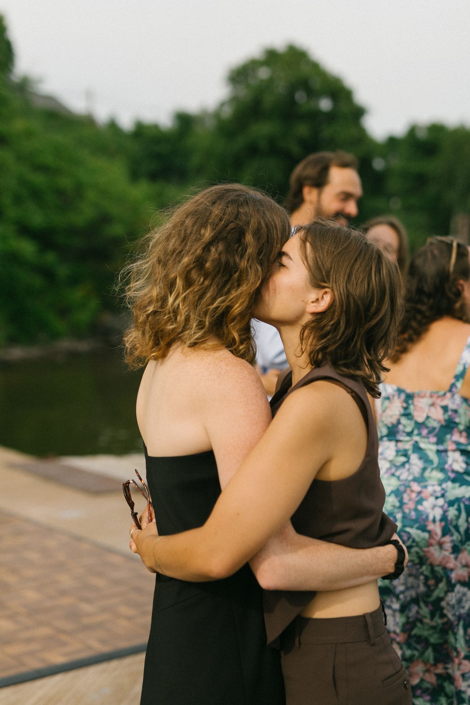 Wedding guests sharing emotional embraces during outdoor celebration.