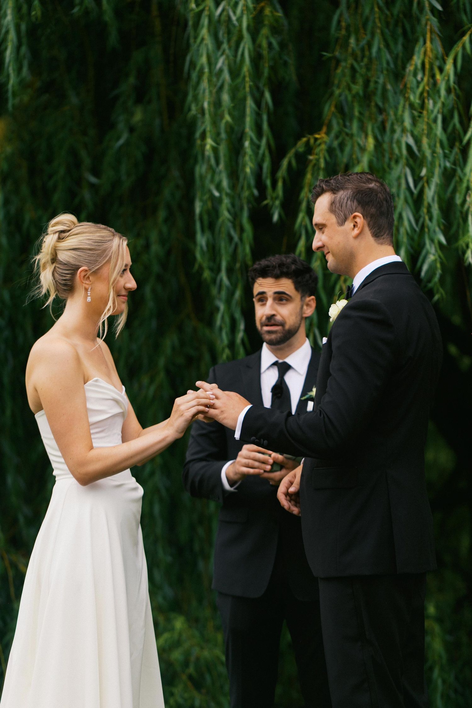 A series of candid wedding ceremony moments showing a couple exchanging rings under a willow tree.