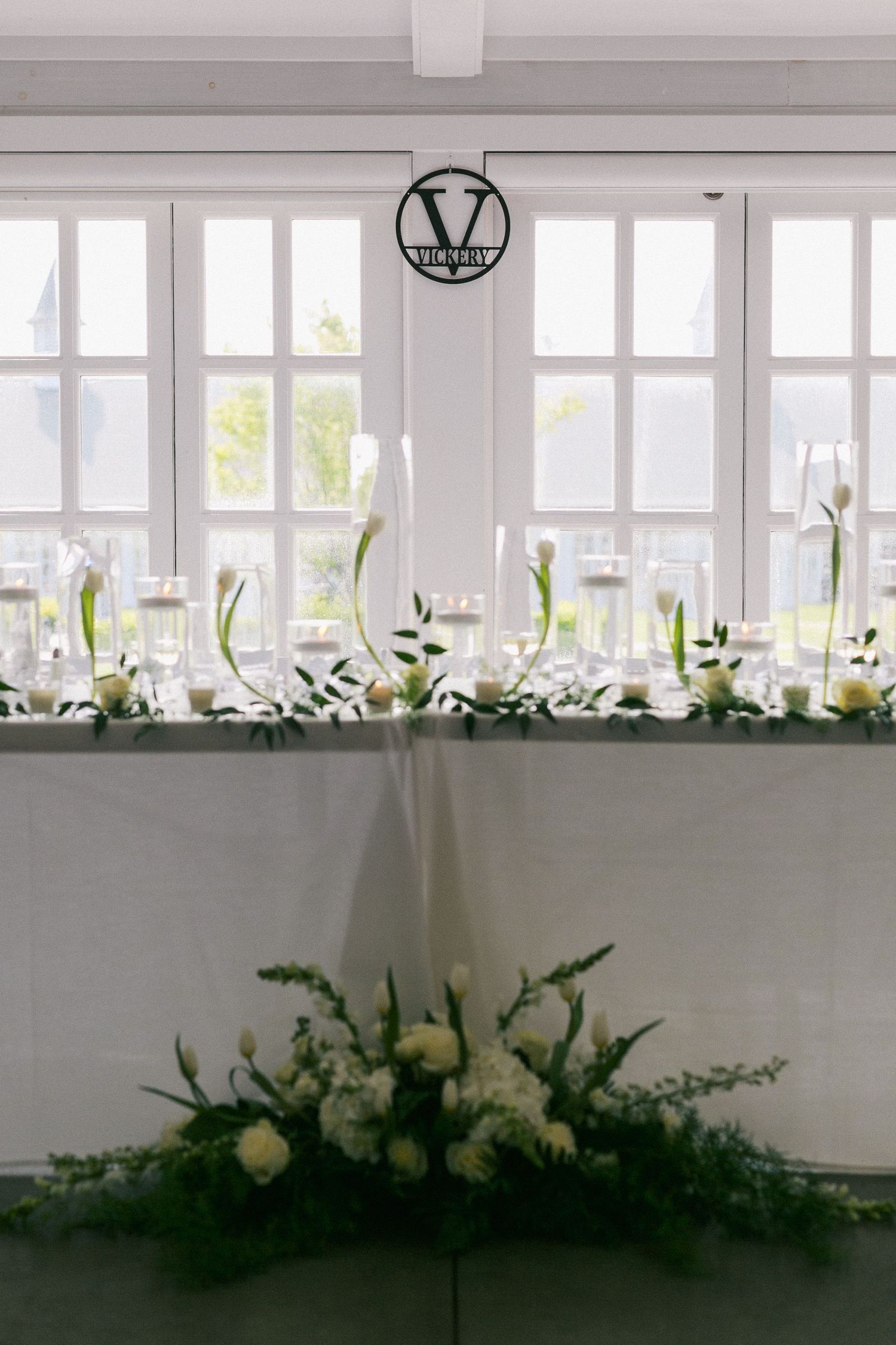 Elegant white floral centerpieces line a windowsill at a wedding reception venue.