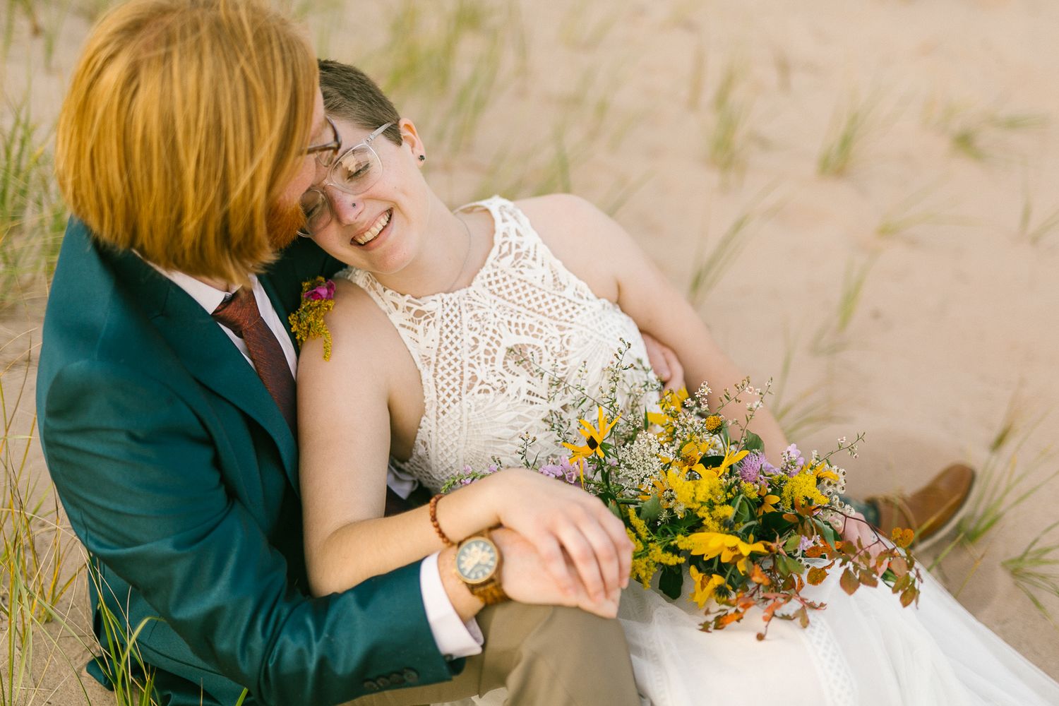 A romantic beach photoshoot featuring a couple embracing among yellow wildflowers.