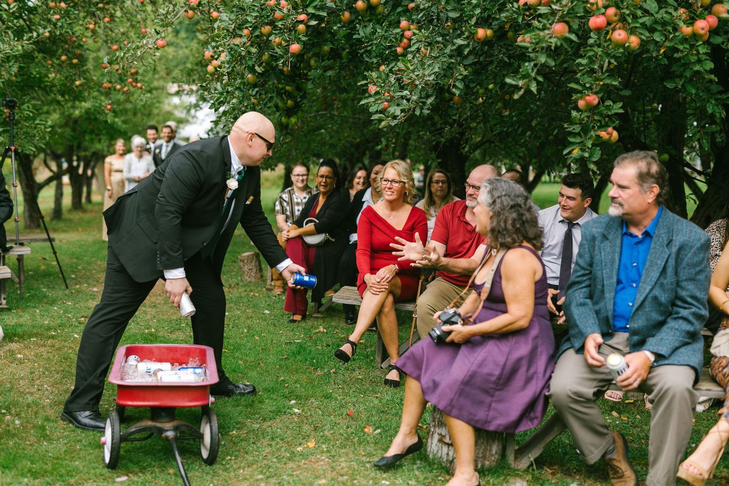 A gathering of guests at an outdoor event sit on chairs while being entertained in a lush green garden setting.