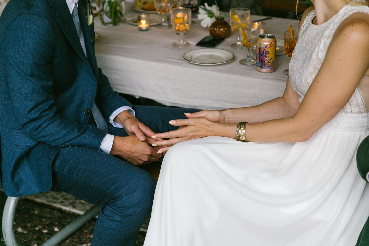 Close-up of hands resting on formal attire at an elegant table setting with candlelight.