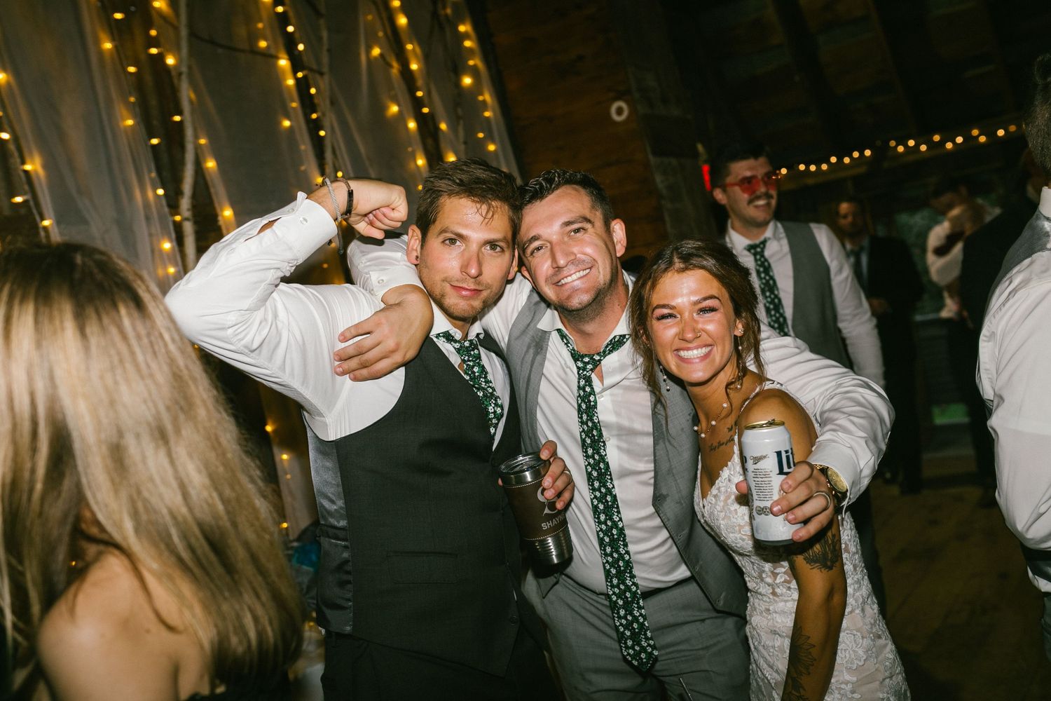 Wedding guests celebrating and posing together at a reception under decorative string lights.