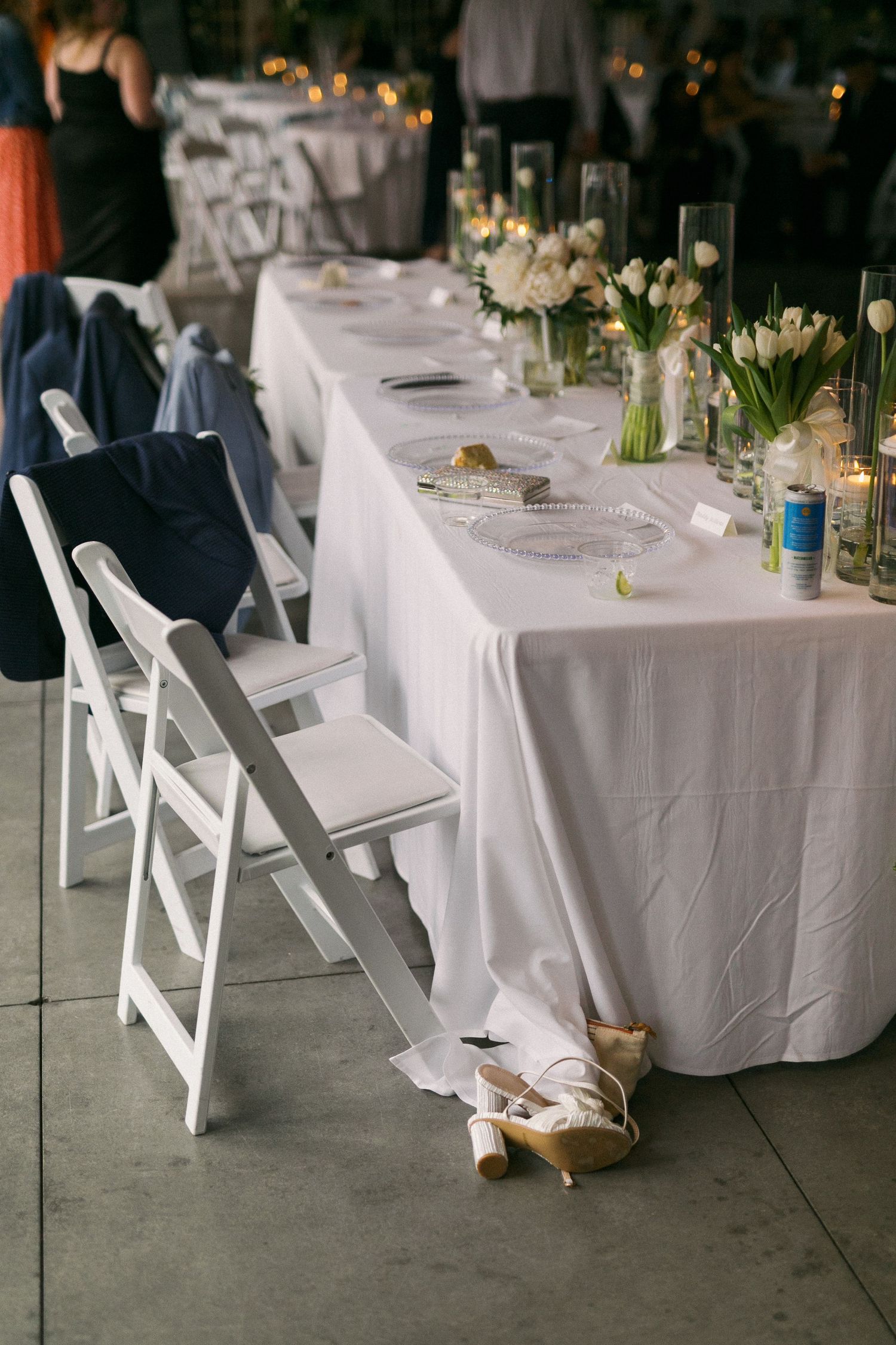 Wedding reception setup with white tablecloths, folding chairs, and elegant table settings.