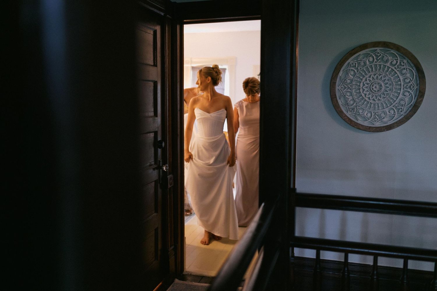 A person in a white dress stands in a dimly lit room with elegant decor and architectural details.