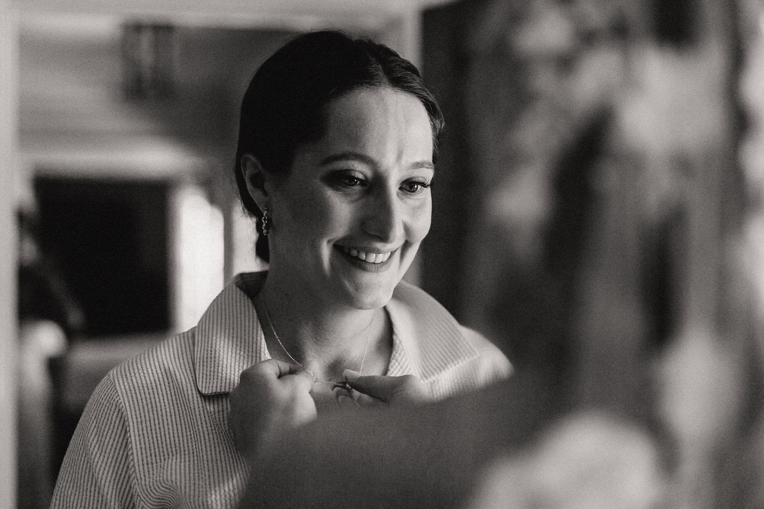 A candid black and white portrait of someone smiling warmly with a collared shirt.