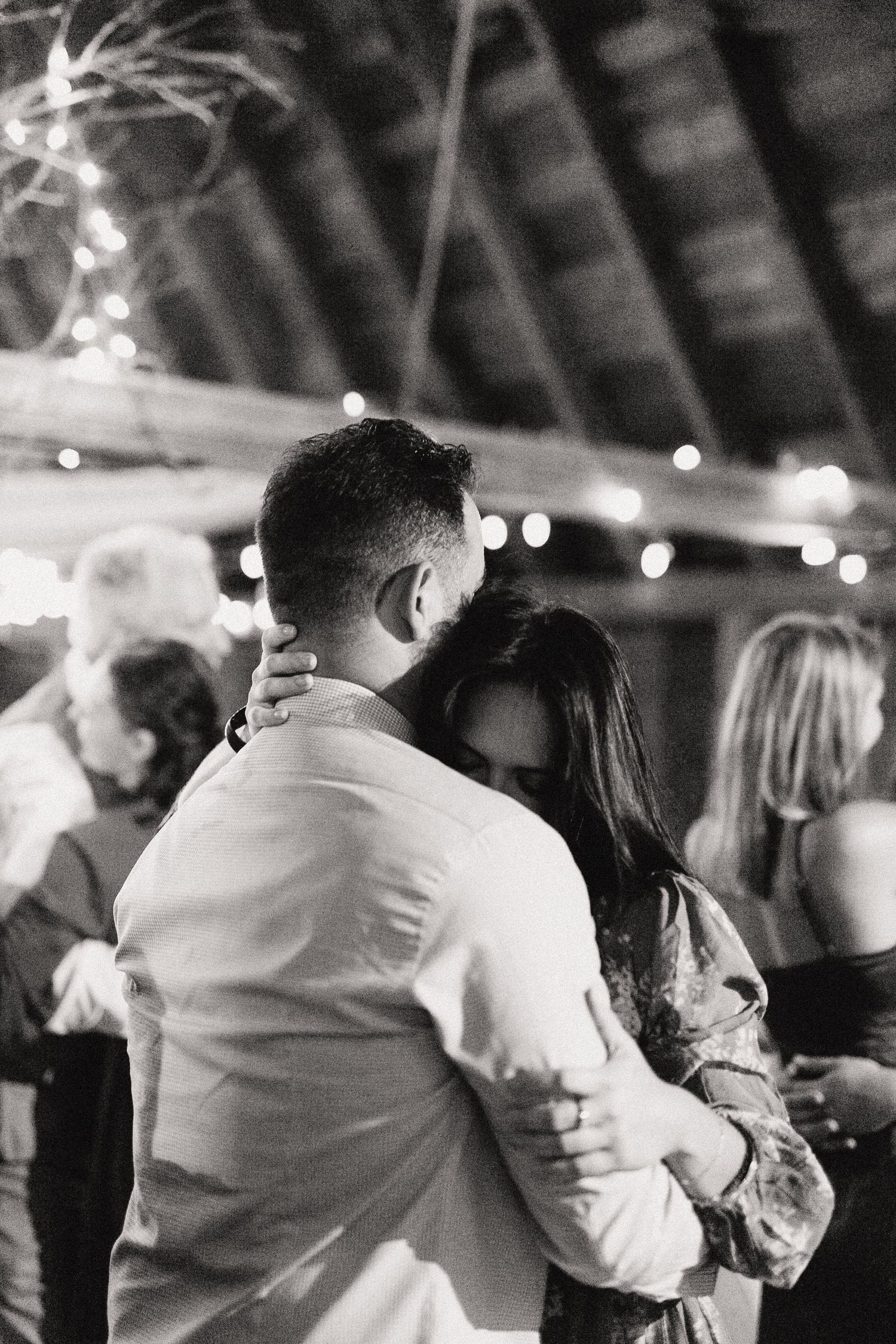 Black and white photo of couple embracing during a dance at an evening reception.