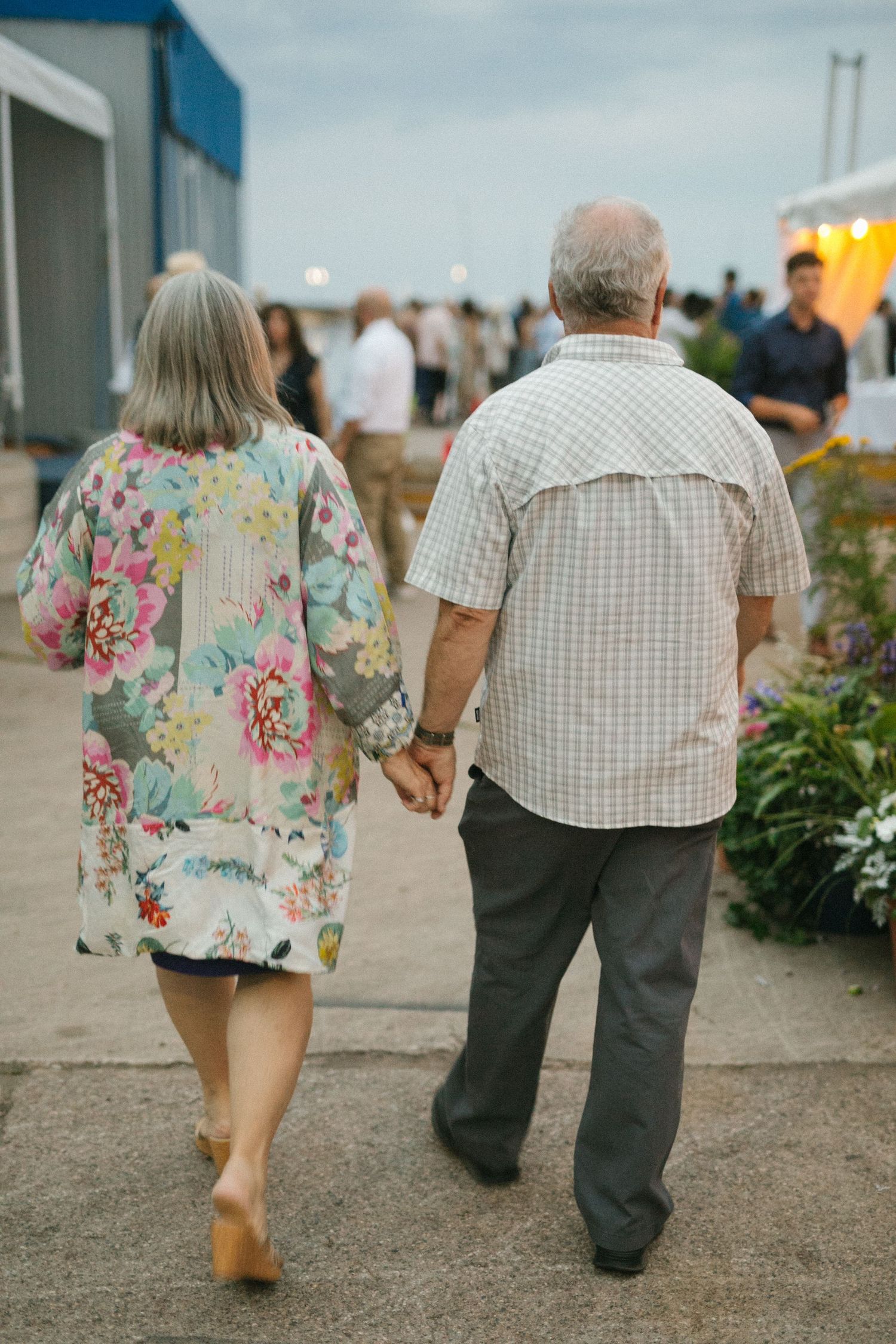 Guests in floral and plaid clothing walking along a seaside path.