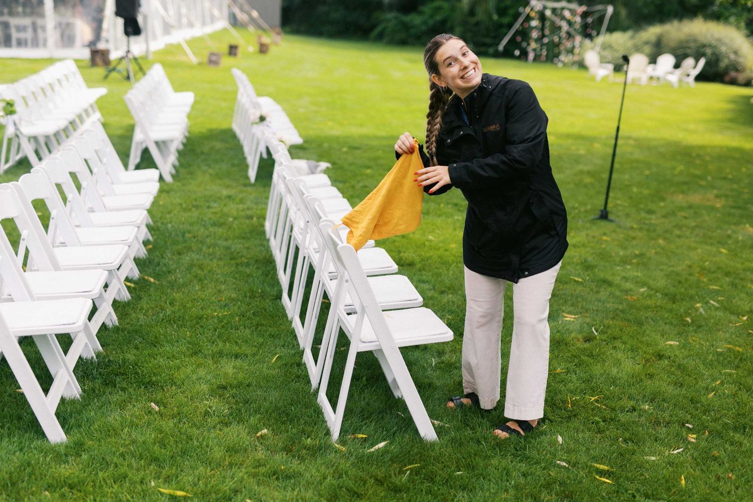 White folding chairs arranged on a green lawn for an outdoor wedding ceremony.