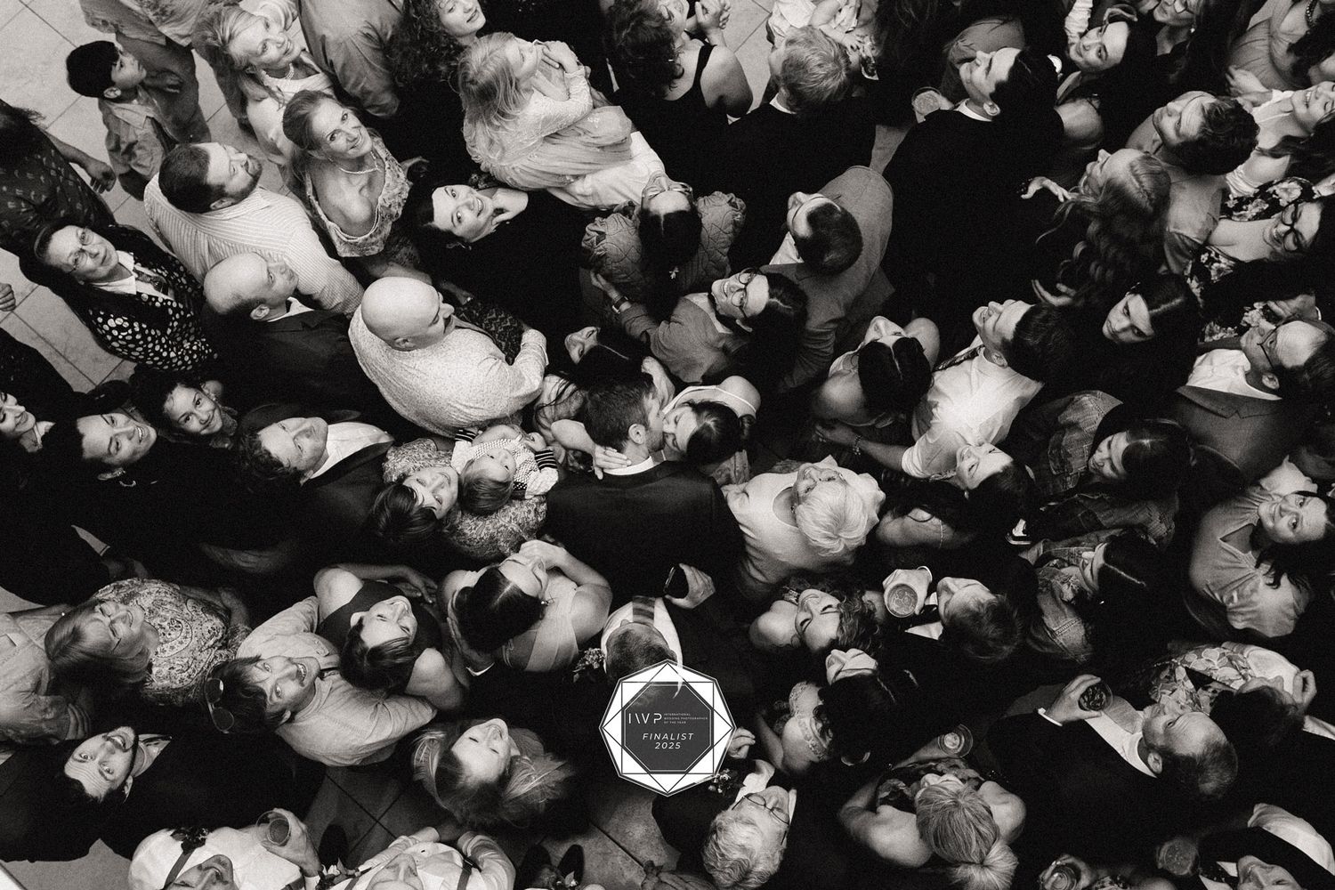 Black and white aerial view of a large crowd of wedding guests gathered together from above.