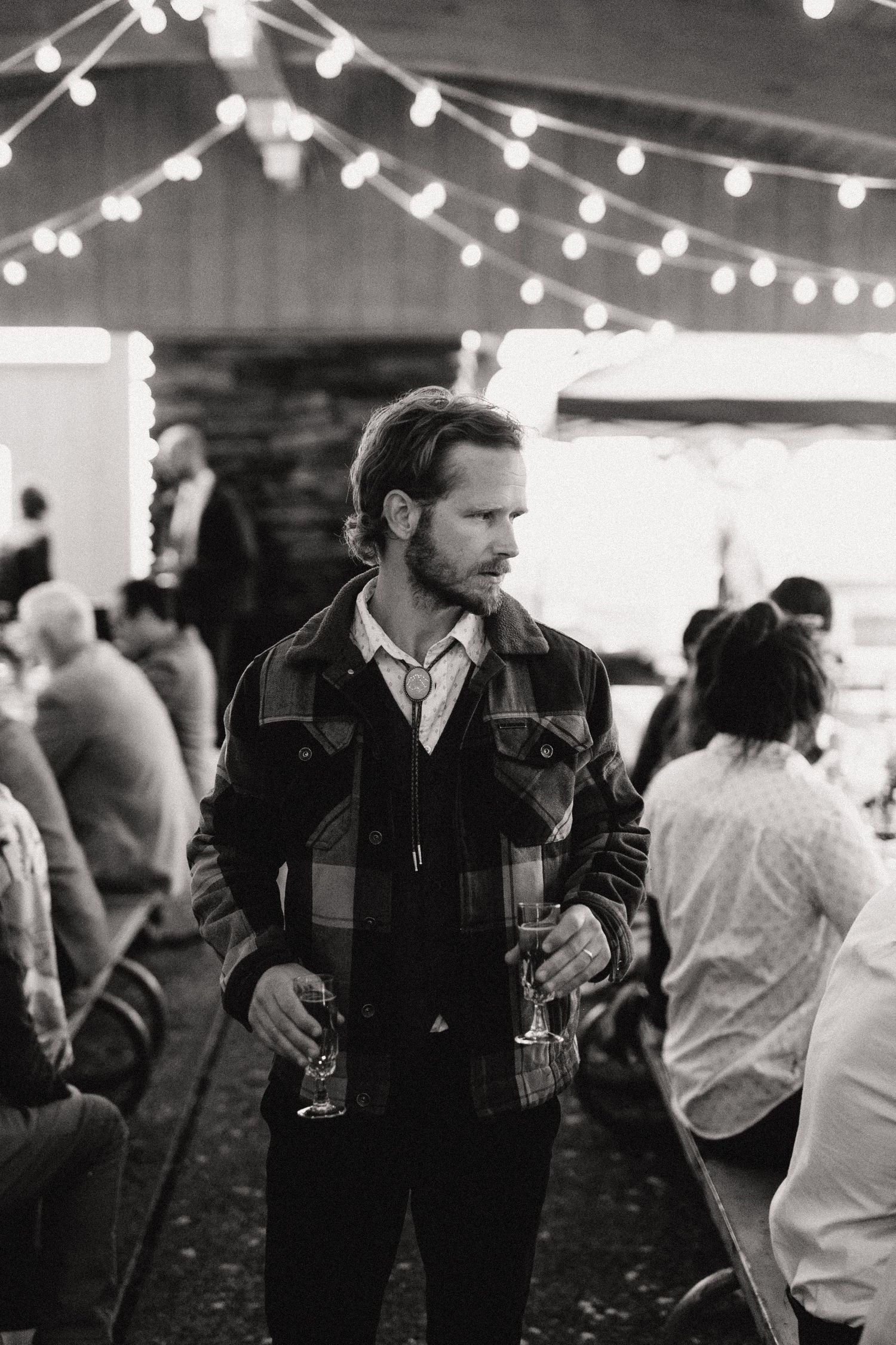 Evening gathering under string lights with partygoers mingling in casual attire.