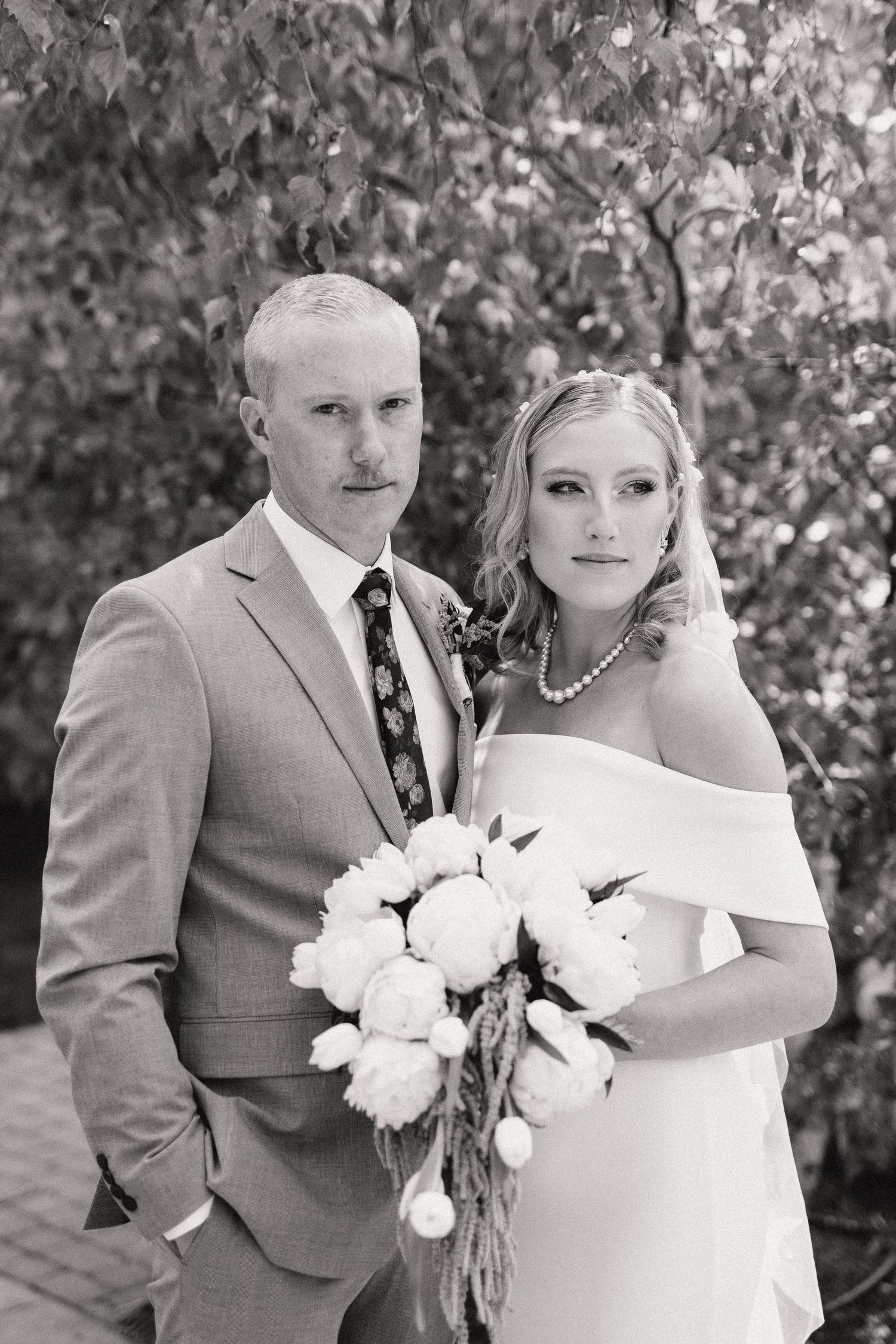 Wedding portrait with white floral bouquet against a natural outdoor background.
