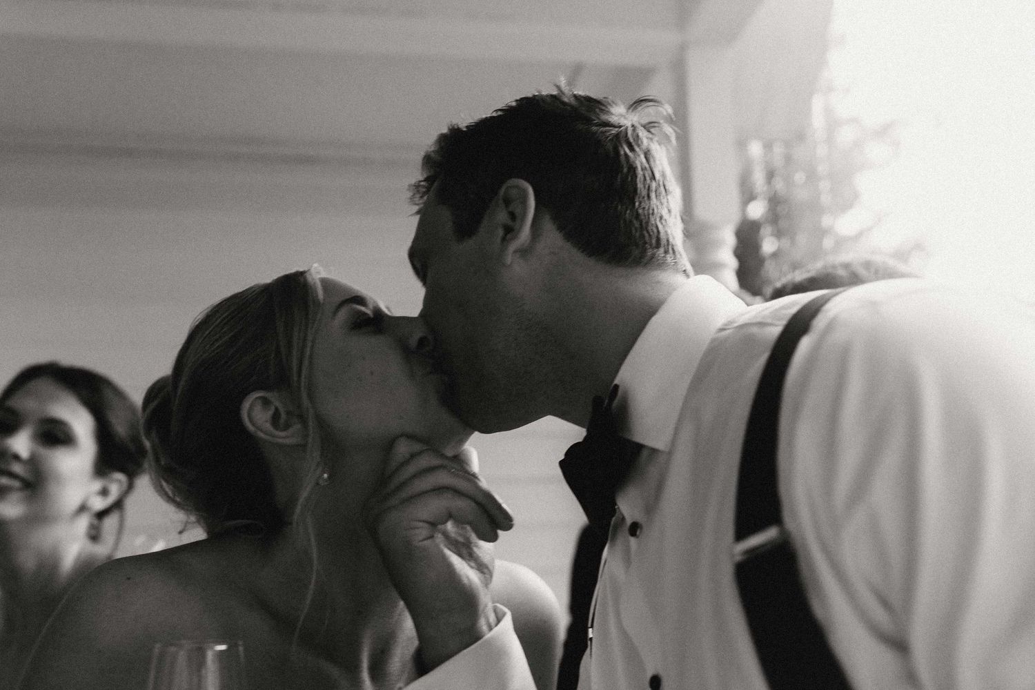 A bride and groom kiss while hiding from the rain.