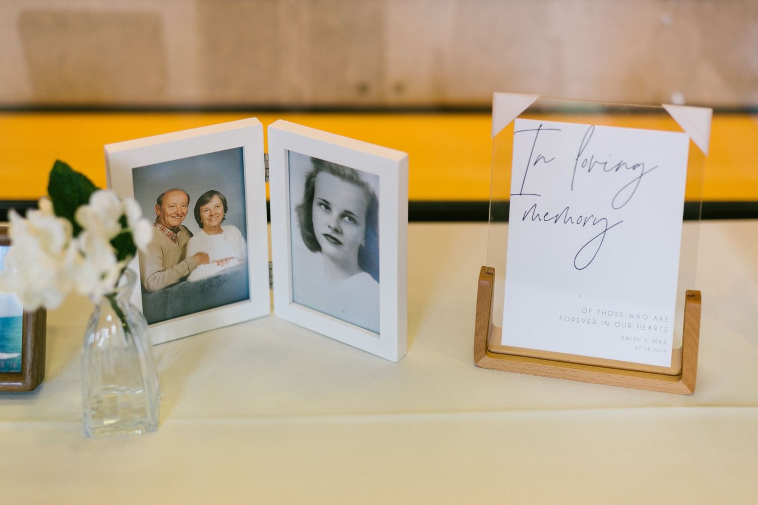 In loving memory wedding table display with framed photos of loved ones and white flowers.