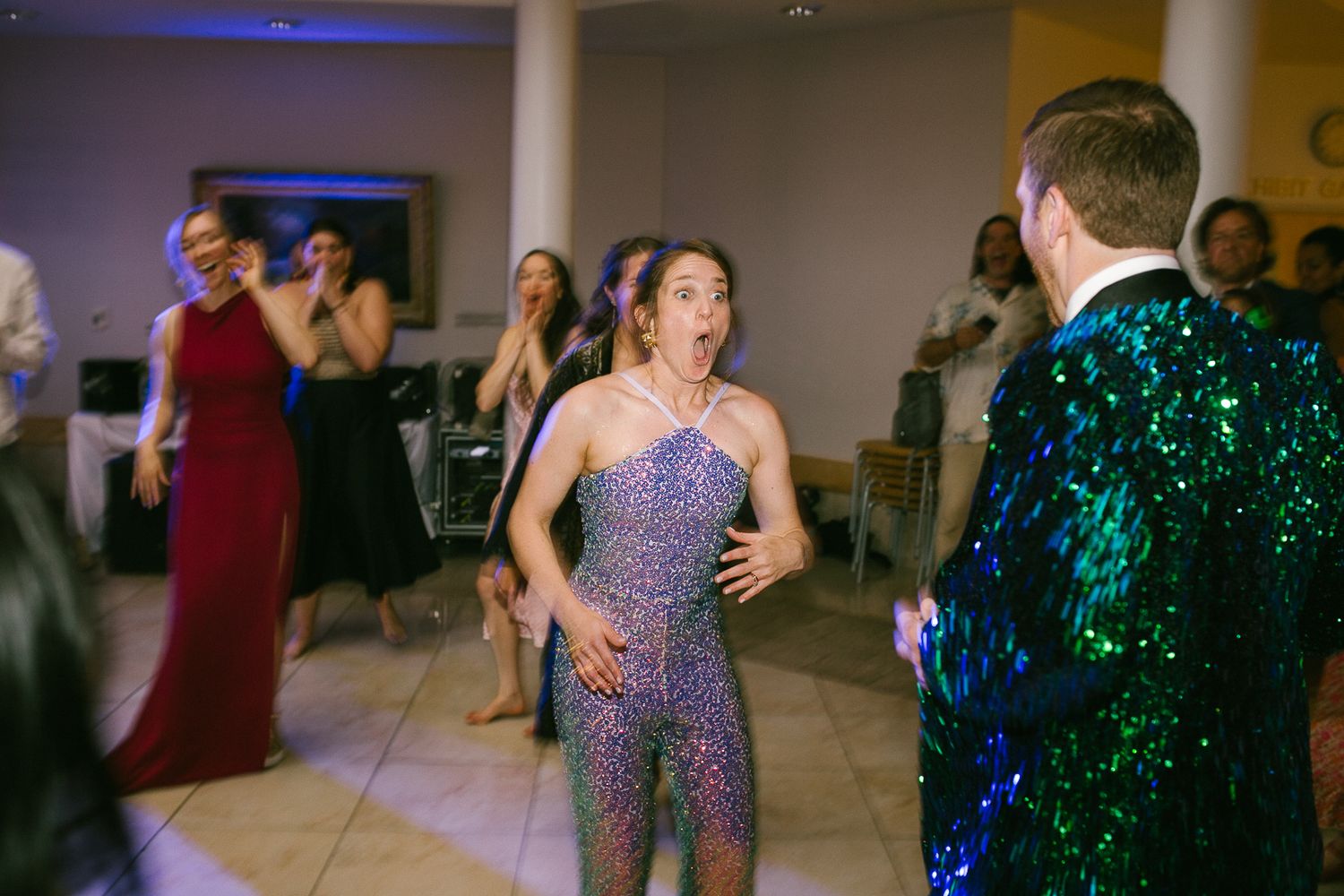 Wedding reception dance floor with colorful disco lights and sparkling dresses.