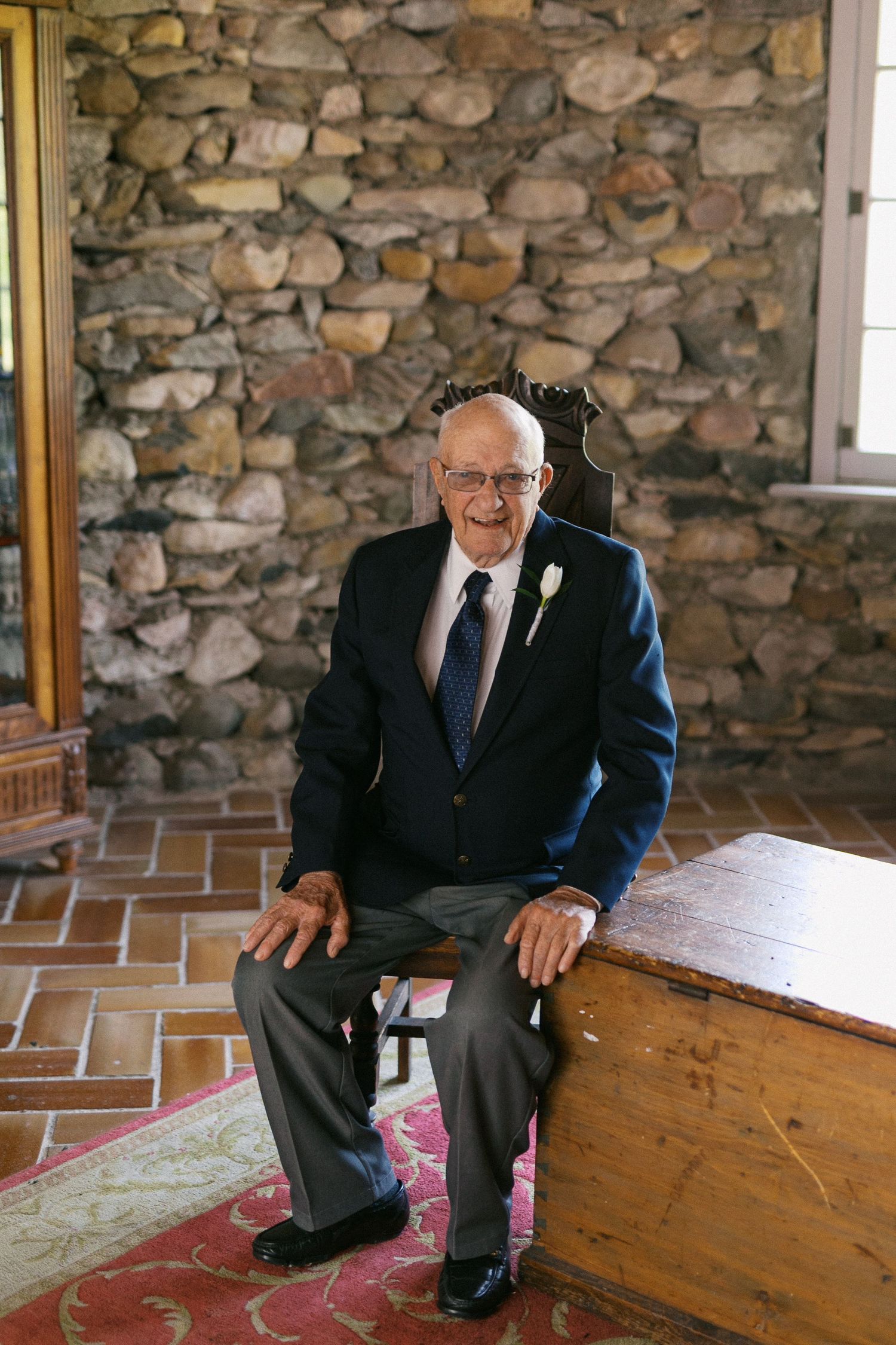 Gentleman in formal attire seated on wooden bench against rustic stone wall in three sequential photos.