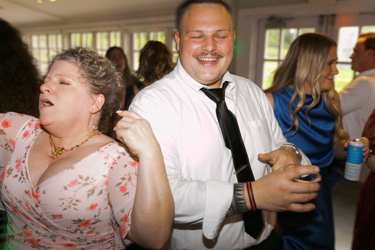 Wedding guests dancing and laughing at a reception celebration.