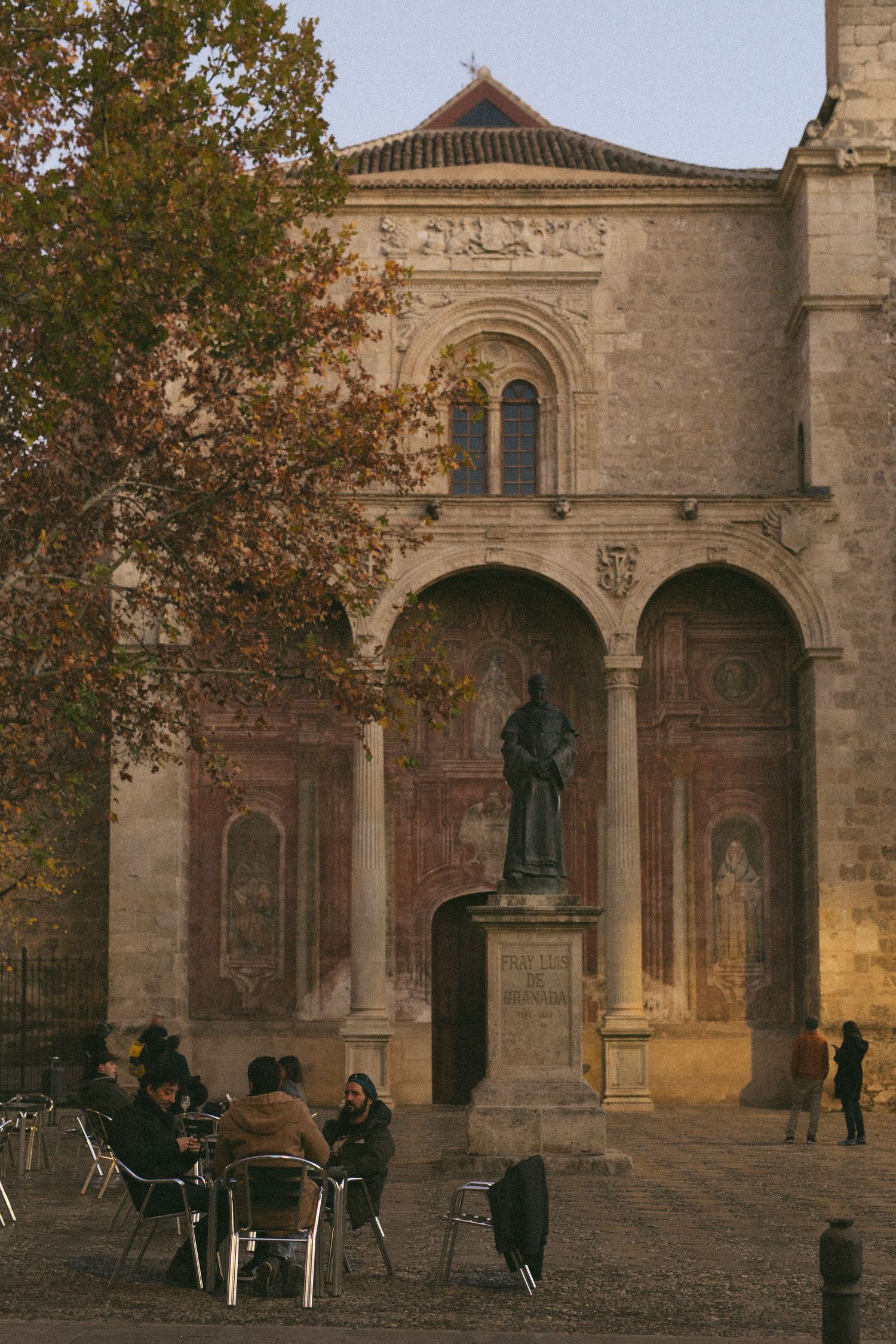 Church courtyard with an arched facade and outdoor cafe seating on a fall afternoon.